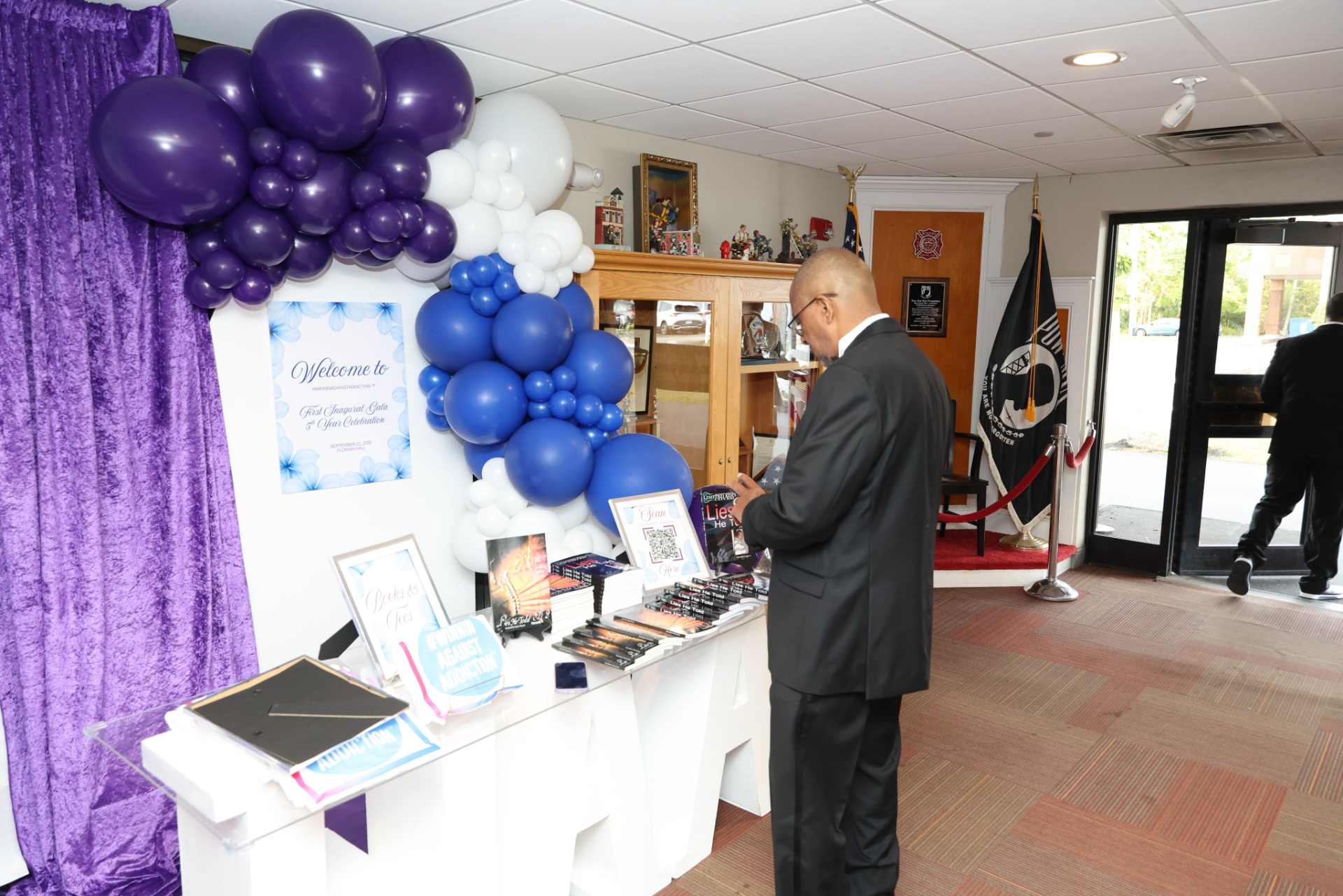 2025 Winnin Against Addiction gala welcome table with purple and blue balloon arch