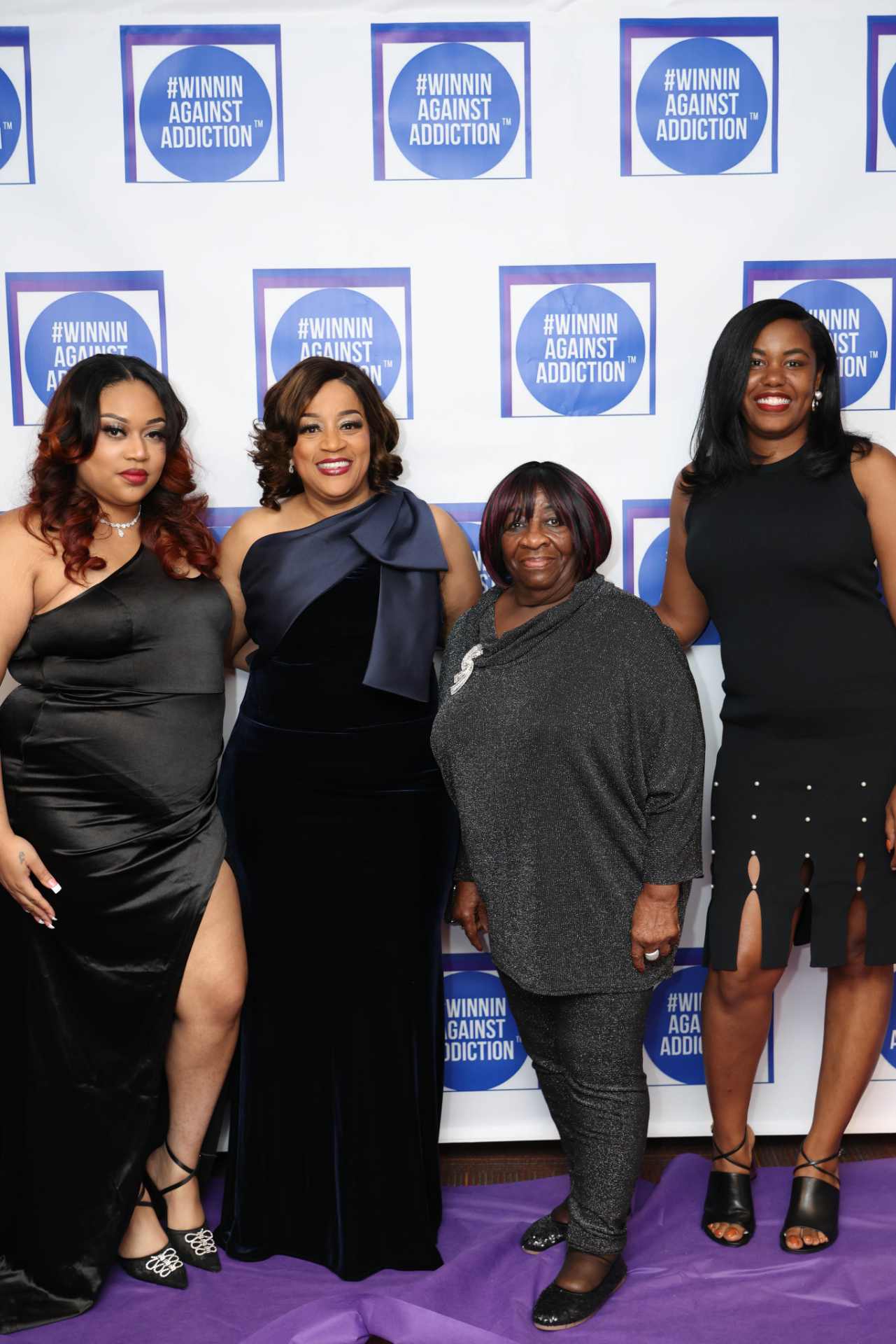 2025 Winnin Against Addiction gala attendees in elegant black dresses on purple carpet