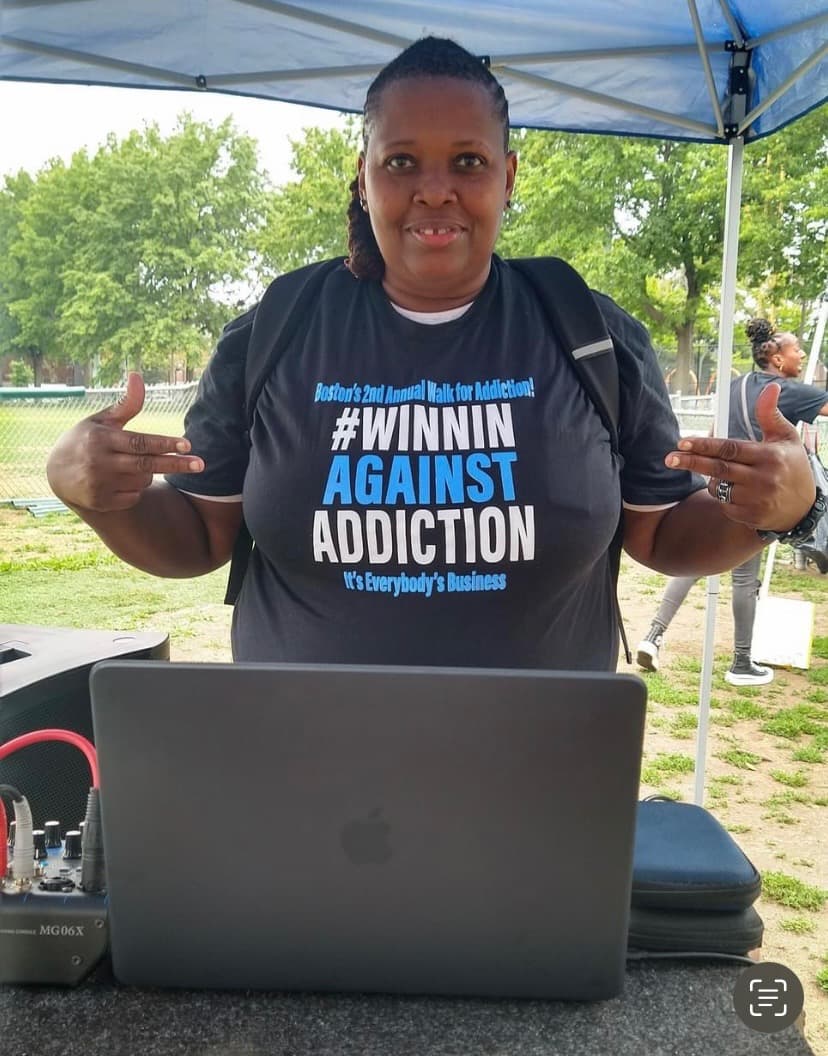 2023 Winnin Against Addiction event coordinator at registration booth wearing branded shirt in Boston