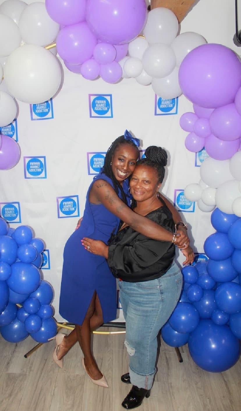 2024 gala attendees embracing at Winnin Against Addiction celebration with balloon arch