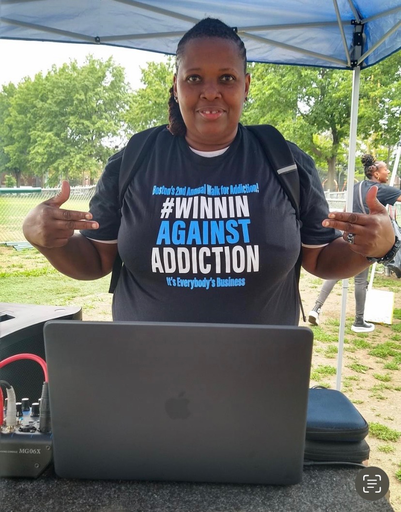 2023 Winnin Against Addiction event coordinator at registration booth wearing branded shirt in Boston