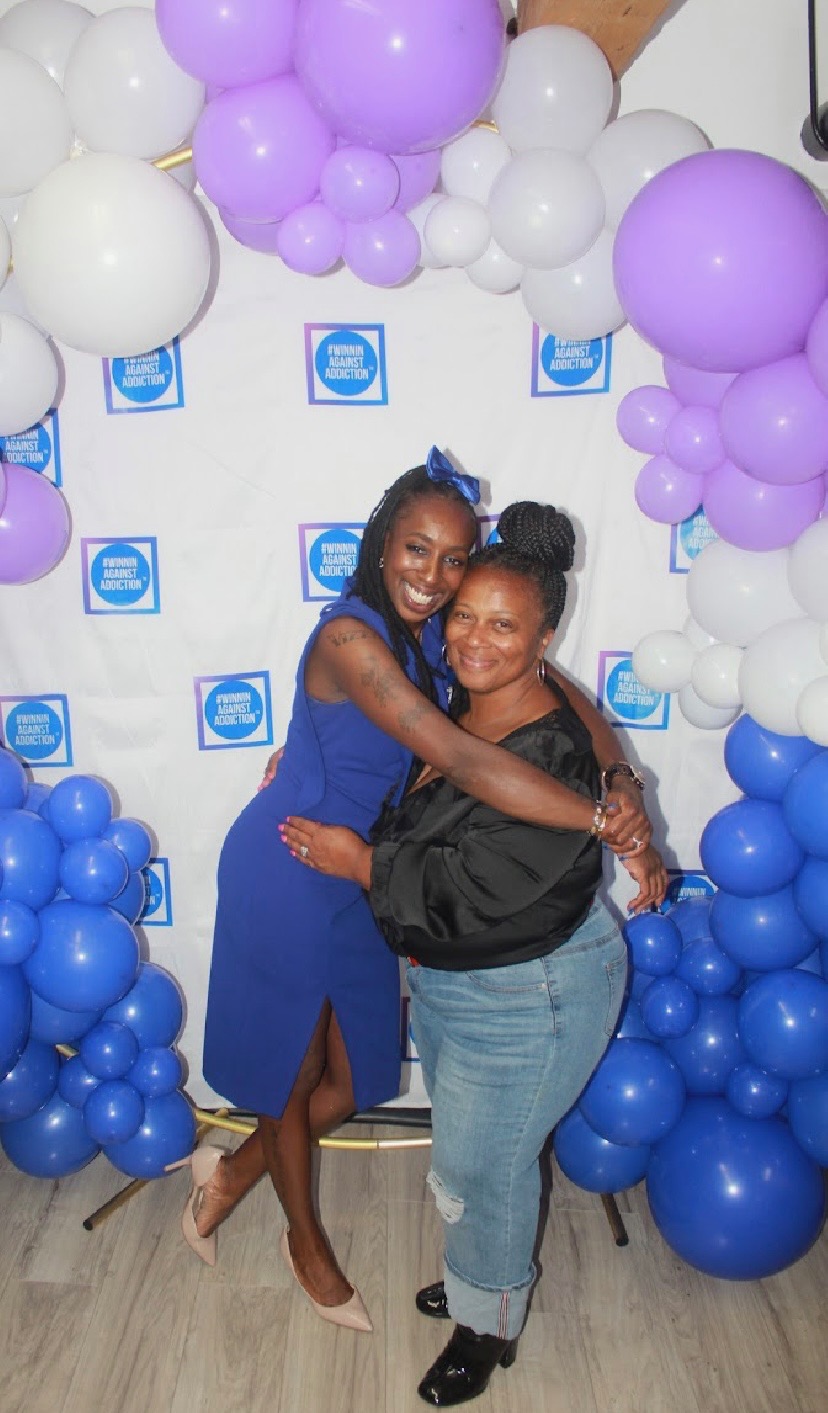 2024 gala attendees embracing at Winnin Against Addiction celebration with balloon arch