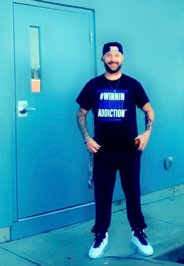 2022 Winnin Against Addiction community advocate in black branded shirt at Boston outreach event