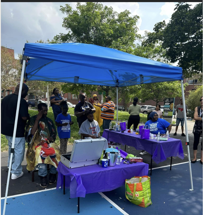 Community outreach event with volunteers serving under a tent